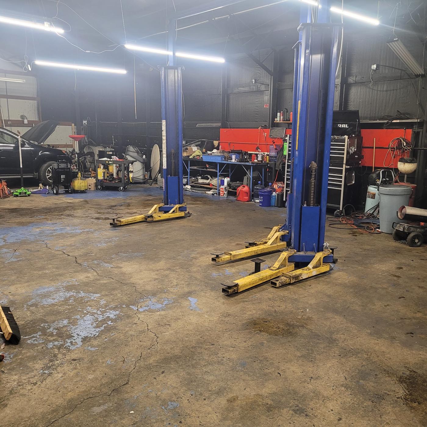 Inside the shop: two-post lifts, the workbench wall, and a car with its hood up